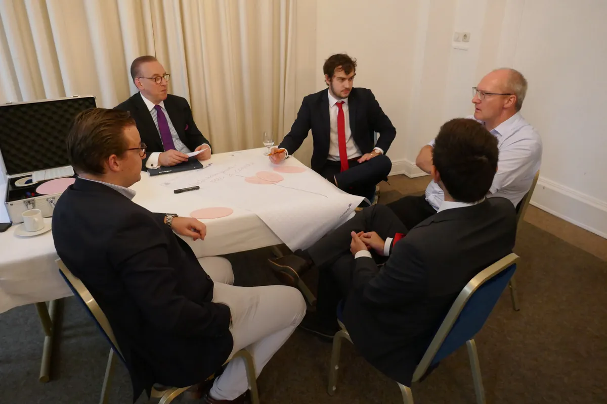 Hermann-Ehlers-Symposion 2022: Arbeitsgruppe aus fünf Teilnehmern diskutiert an einem Tisch mit Papierbogen und Moderationskarten